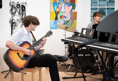 Students playing piano and guitar in school
