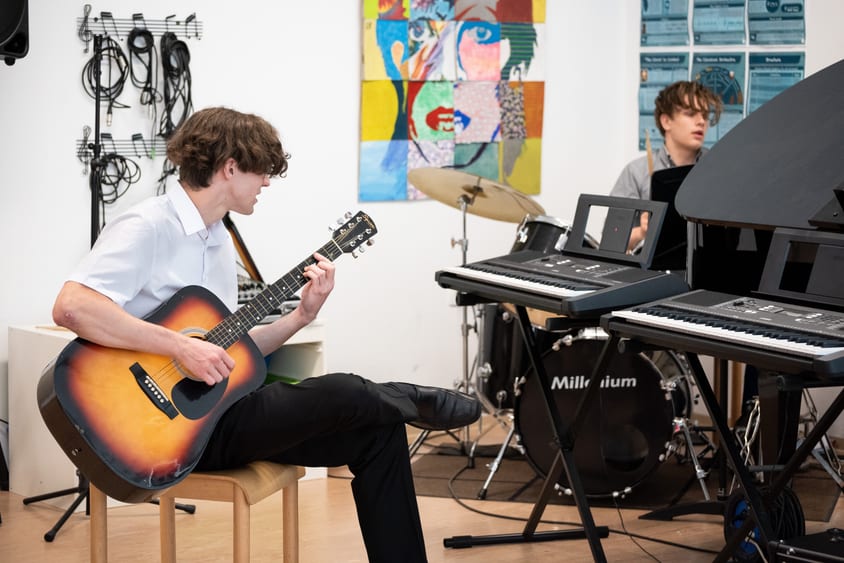 Students playing piano and guitar in school